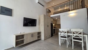 Un apartamento moderno con comedor, kitchenette y televisor montado en la pared.