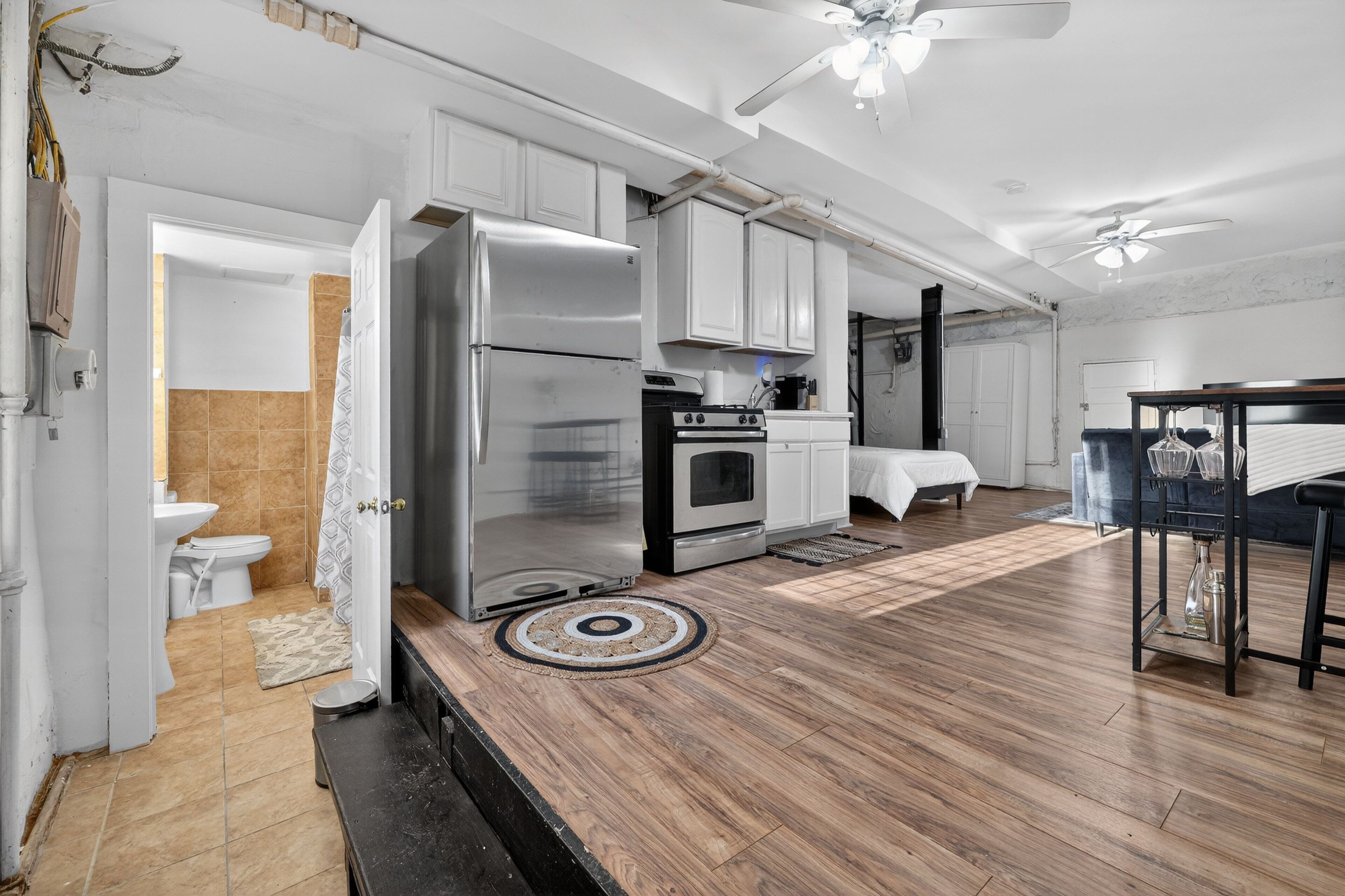 A spacious kitchen with white cabinets, a stainless steel refrigerator, and a black oven.
