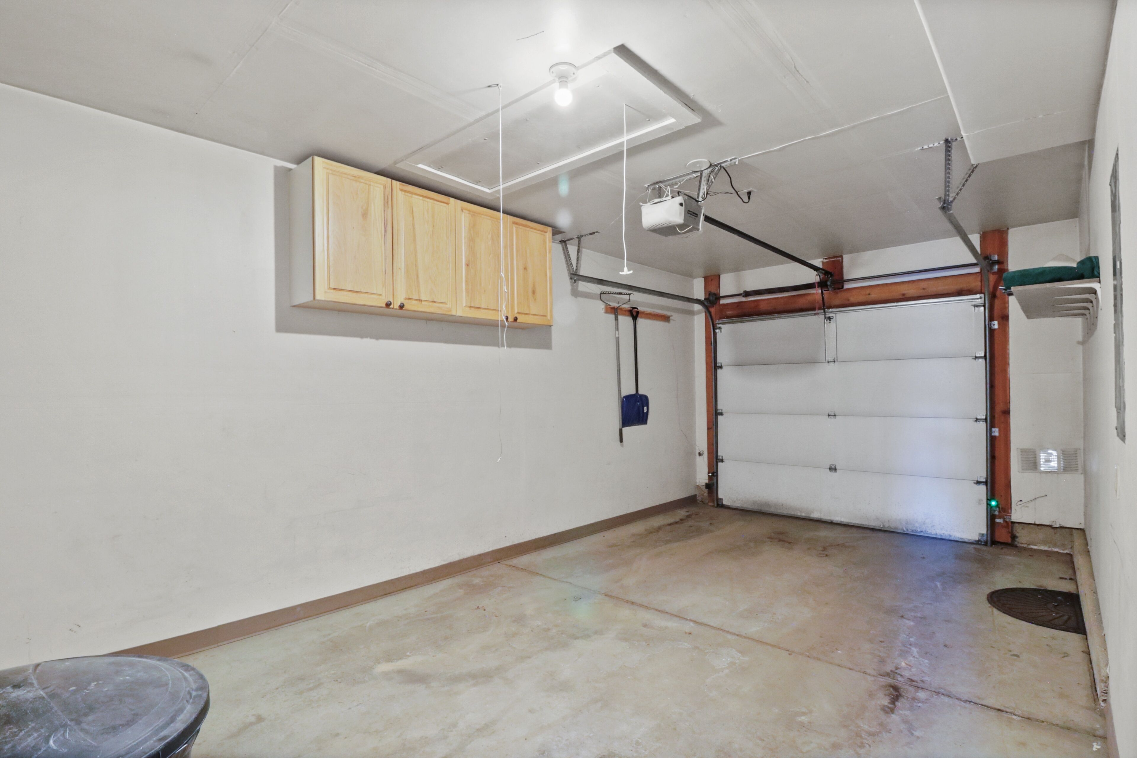 Eine Garage mit Holzkasten, einer Garagentür und einer Decke mit sichtbaren Balken und Leuchten.