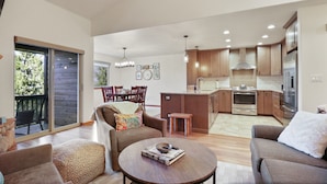 A spacious living area with a dining table, sofas, and a kitchen in the background. - 97 Lookout Ridge 2 Bedroom Townhouse (Dillon)