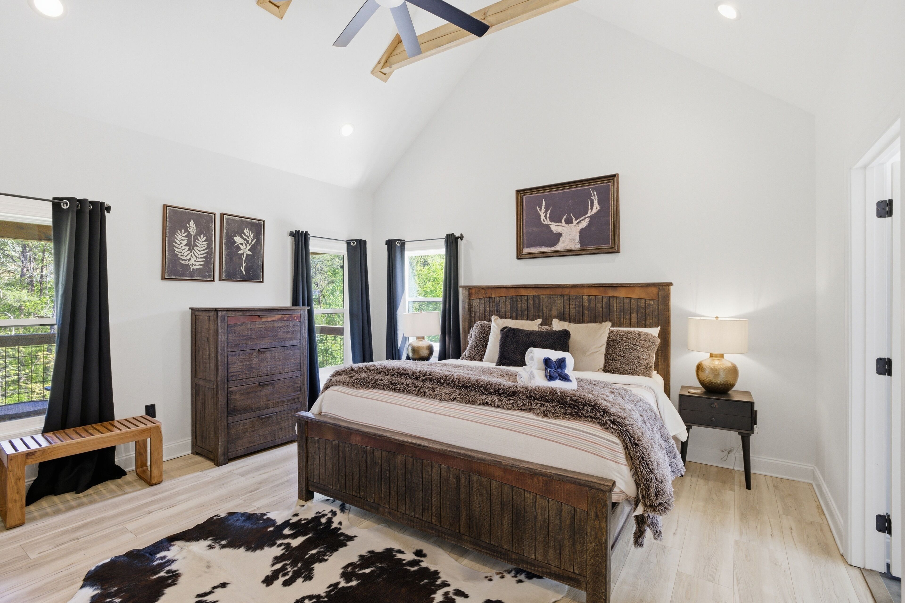 A bedroom with a wooden bed, a nightstand, a bench, and a cowhide rug.