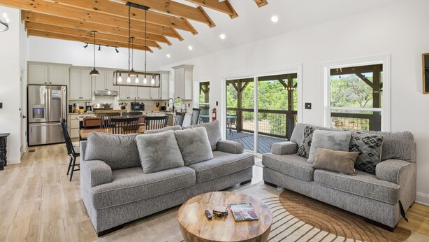 Ein großzügiger Wohnbereich mit zwei grauen Sofas, einem Holztisch und einem Deckenventilator.