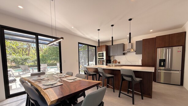 Een moderne keuken met een groot eiland, barkrukken en een inbouwkoelkast.