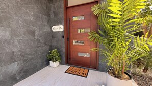 Een moderne entree met een houten deur, een bordje met de tekst 'Casona Sur', een kleine potplant en een deurmat.