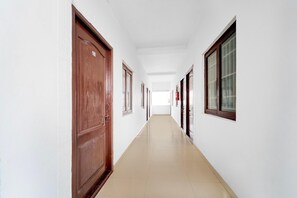 A long, narrow hallway with white walls and wooden doors. - Hotel O Coimbatore International Airport (Coimbatore)