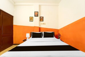 A hotel room with a bed, a nightstand, a lamp, and two framed pictures on the wall.