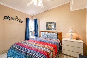 A bedroom with a bed, a nightstand, a lamp, a mirror, and a window with curtains. - Casa de la Suerte – Ocean View, Las Conchas (Puerto Penasco)