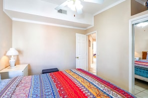 Une chambre à coucher comprenant un lit, une table de chevet, une lampe et une porte donnant sur une autre pièce.