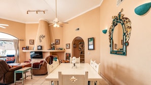 Una sala de estar acogedora con comedor, chimenea y un espejo grande con marco decorativo.