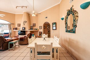 Un salon chaleureux comprenant un coin repas, une cheminée et un grand miroir agrémenté d’un cadre décoratif.