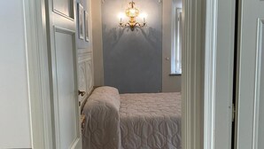 Una camera da letto con un letto, una lampada a parete e una porta che dà su un'altra stanza.