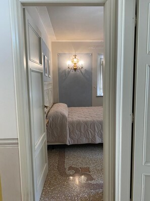 Ein Schlafzimmer mit einem Bett, einer Wandlampe und einer Tür zu einem anderen Raum.