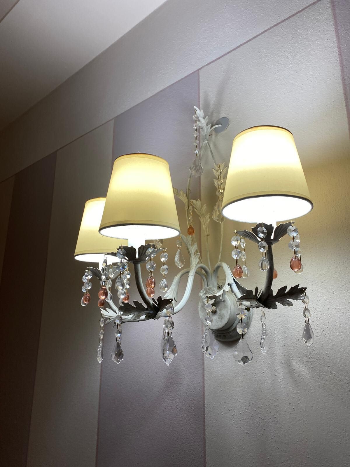 A chandelier with three lampshades and crystal decorations.