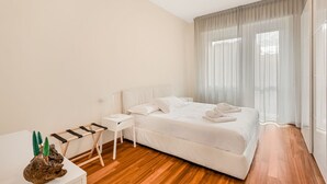 Ein modernes Hotelzimmer mit einem großen Bett, einem kleinen Tisch und einem Nachttisch.