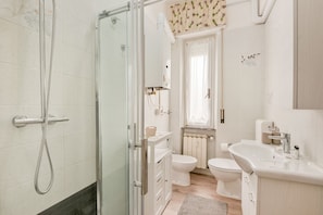 Een douche, een bidet, handdoeken, toiletpapier