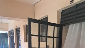 Un pasillo con una puerta negra, una cortina blanca y suelo de baldosas.