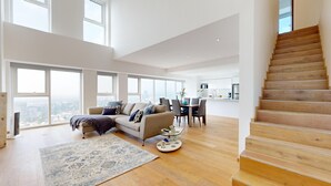 A spacious living room with a large window, a wooden staircase, and a dining area. - Start 2026 in a penthouse with amenities (Ciudad de México)