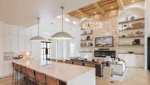 A spacious kitchen with a large island, wooden beams, stone wall, and built-in shelving. - Sleeps 58! Parade Home! 30 Person Spa! (St. George)