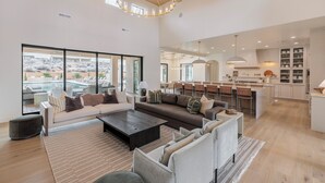 A spacious living area with a large sofa, a coffee table, and a view of a pool. - Sleeps 58! Parade Home! 30 Person Spa! (St. George)