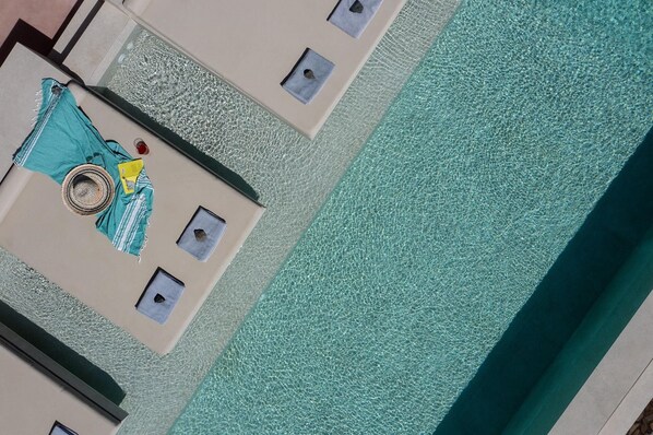 Una piscina con agua cristalina, una toalla y un sombrero en el borde.