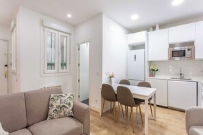 A modern kitchen with white cabinets, a built-in microwave, and a dining area with a white table and chairs. - A two-bedroom apartment with a second room for guests, set in the eclectic heart of Malasaña, steps from Tribunal and the city's vintage shops, record stores and bars. (MADRID)