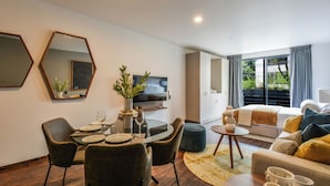 A modern living room with a dining area, a sofa, and a TV. - The Sterling Condesa (Mexico City)