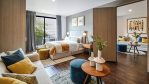 A modern hotel room with a large bed, a sofa, a coffee table, and a view of the outdoors. - The Sterling Condesa (Mexico City)