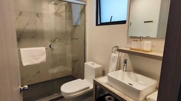 Deluxe kamer | Badkamer | Een douche, een haardroger, handdoeken, zeep