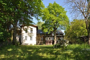 Una casa tradicional amb jardí, envoltada d'arbres.
