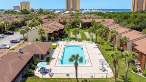 Un resort con una piscina centrale, diverse camere per gli ospiti e vista sull'oceano.