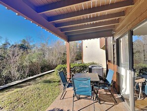 Un patio al aire libre con una mesa y sillas, una zona cubierta y vistas del paisaje circundante.