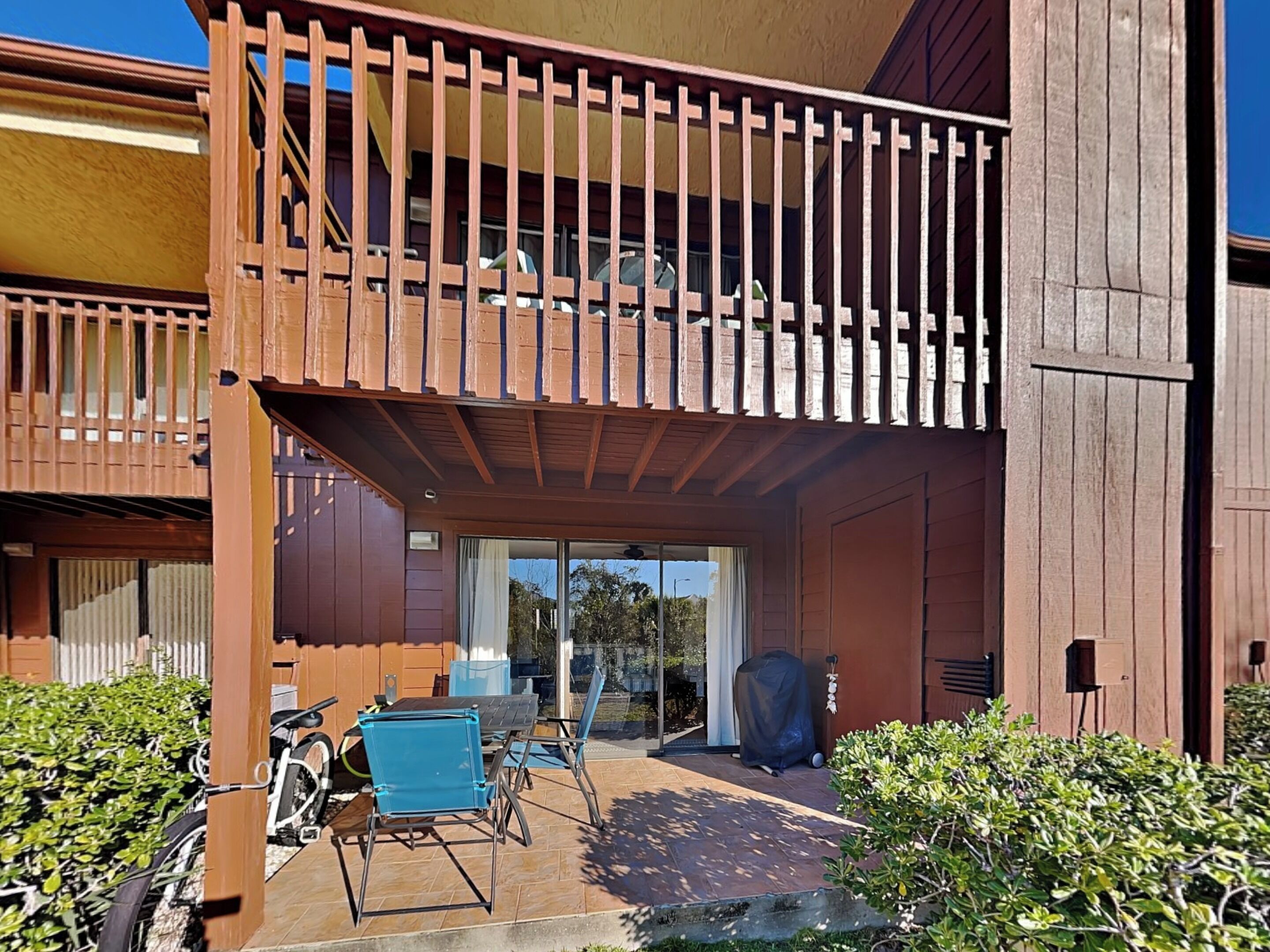 Un bâtiment à deux étages doté d’un balcon, d’un espace extérieur aménagé pour s’asseoir et d’une terrasse couverte.