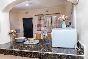 A kitchen with a marble countertop, a white refrigerator, and a vase with flowers on the counter.