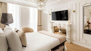 A luxurious bedroom with a large bed, a chandelier, a fireplace, and a television. - A BLEND OF CLASSIC PARISIAN CHARM WITH MODERN SOPHISTICATION NEXT TO THE LOUVRE (Paris)