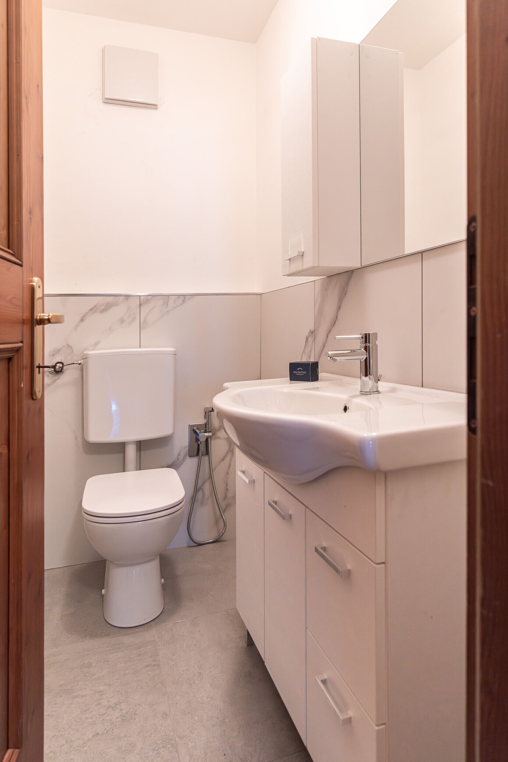 A bathroom with a toilet, sink, and cabinet.