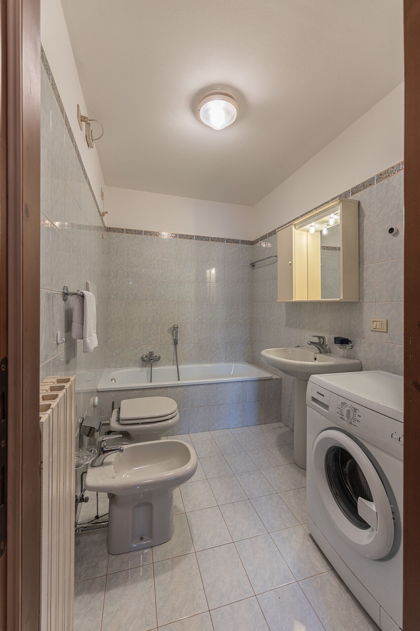 Ein Badezimmer mit Badewanne, Toilette, Bidet, Waschbecken und einer Waschmaschine.