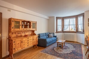 Un salon avec un canapé bleu, un meuble en bois et un tapis à motifs.