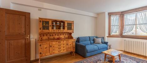 A living room with a wooden cabinet, blue sofa, and a patterned rug.
