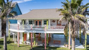 A two-story house with a balcony, a covered patio, and a fenced yard. - Casa Bella - 4 bedroom, Gulf View, Cargo Lift, Outdoor Bar, Fenced Yard, (Crystal Beach)