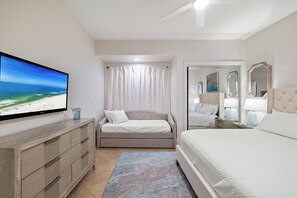 A bedroom with a bed, a TV, a dresser, and a window with curtains. - Turquoise Place 2102C by Liquid Life (Orange Beach)