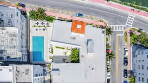 Vista aérea de una azotea con piscina, cancha de tenis y zona cubierta con asientos.