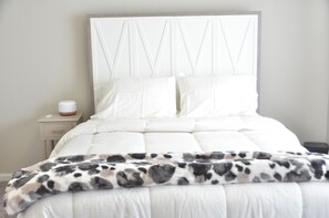 Un lit bien fait, avec une tête de lit blanche et un plaid à motifs.