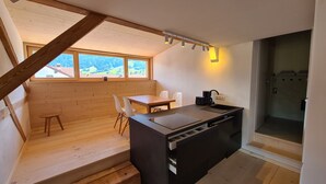 Una cocina compacta con una mesa y sillas de madera, horno empotrado y ventana con vistas a un paisaje pintoresco.