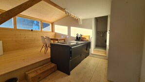 Una cocina moderna con detalles de madera, un comedor con sillas y vistas al exterior.