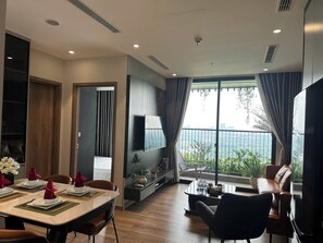 Un salon moderne comprenant un coin repas, un téléviseur à écran plat fixé au mur et un balcon offrant une vue sur la ville.