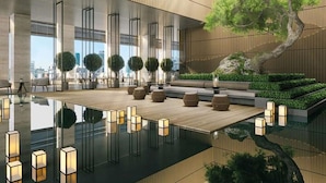 A modern indoor space with a wooden ceiling, large windows, and a central water feature.