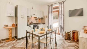 Una cocina compacta con armarios blancos, una mesa de comedor para cuatro personas y un suelo con patrón de espiga.