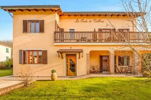A two-story building with a balcony, a sign reading "La Corte di Valtori", and outdoor seating. - La Corte dei ValEmi is a complex of 4 apartments located in Riccò del Golfo, in a peaceful area surrounded by greenery. It is ideal for those looking to relax away from the crowds while staying within a short distance of La Spezia and the Cinque Terre.  (Riccò del Golfo di Spezia)