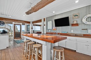 A nautical-themed kitchen with a wooden bar area, white cabinetry, and a large TV mounted on the wall. - 🌴 Gulf Front Home - Private Pool - Sweet Retreat 🌴 (Indian Pass)