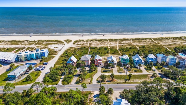Vista aérea de una zona residencial costera con casas, una carretera y una playa.